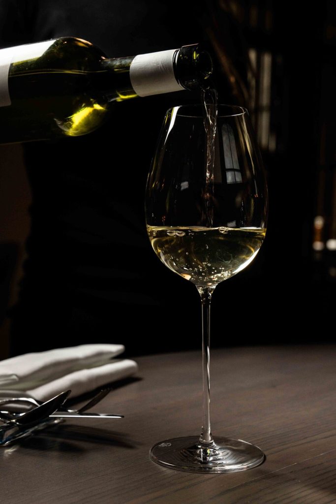Witte wijn wordt ingeschonken in een glas